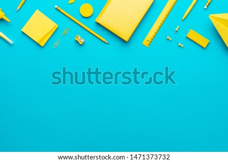 Top view photo of yellow school stationery on turquoise blue background with copy space. Flat lay image of different stationery in order as back to school concept