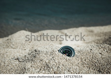 compass on the sands with water background