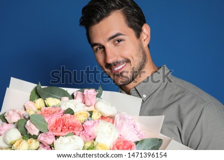 Young handsome man with beautiful flower bouquet on blue background