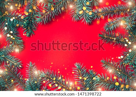 Fir branches with blurred lights garland on a red background. Christmas wallpaper. Flat lay, copy space.