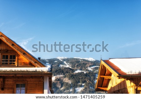 Deep snow covers a rooftop in the Austrian alps on a bright sunny but cold winter day.