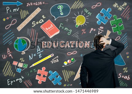 Businessman with creative education sketch on dark wall background. Knowledge and think concept 