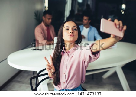 Positive female showing v-sign for taking funny pictures using application for blogging on smartphone gadget, Caucasian hipster girl with duck face clicking selfie photos via modern mobile phone