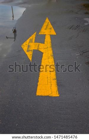 Yellow arrow traffic sign direct way and split to the left on a street road