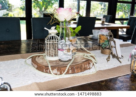 A wedding table setting, rustic style with a rose, succulent plant and string of pearls.