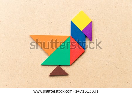 Color tangram puzzle in duck, swan or goose shape on wood background