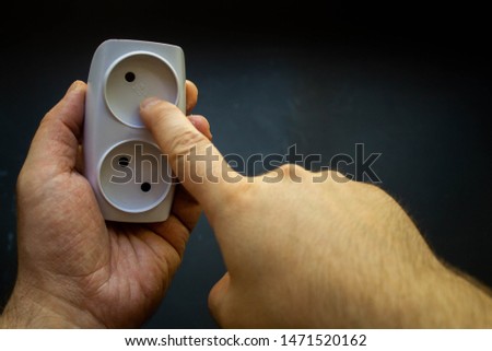 man arm hold white socket, index finger, black background