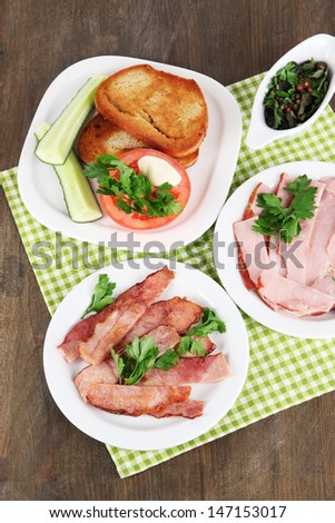 Bacon on plates on napkin on wooden table