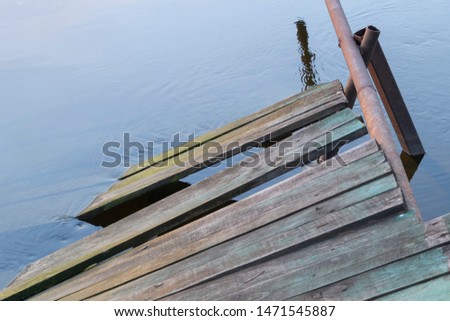 An old wooden pier closeup. Ruined construction drowned in water. Bright picture. 