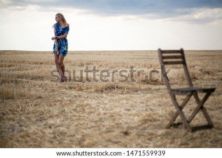 Beautiful girl with blond hair in a field with a chair