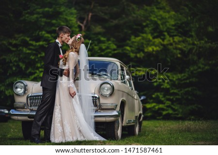 Bride kissing groom, newlywed wedding couple is sit in a retro car on a country road for honeymoon after the ceremony. The best day and marriage. Just married.