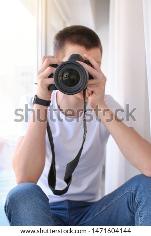 Teenage boy with photo camera near window