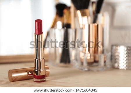 Bright lipstick in gold tube on dressing table, space for text