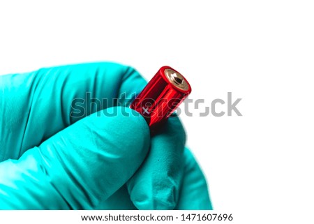 AA battery in hand on a white background. The electrician's hand in the rubber glove holds the AAA batteries for replacement. Plus mark (sign)