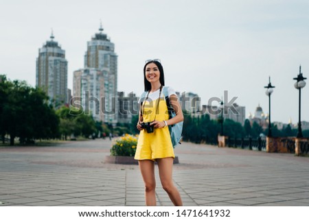 attractive and asian woman in overalls holding digital camera 