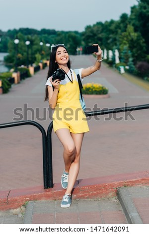  asian and attractive woman holding digital camera and taking selfie 