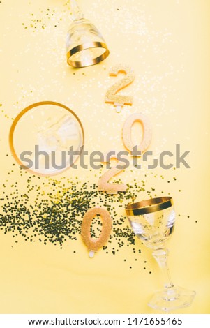New Years Eve celebration background with champagn glass, 2020 number made with golden glitter candles, christmas decoration around, flatlay over a golden board, luxury  holiday concept
