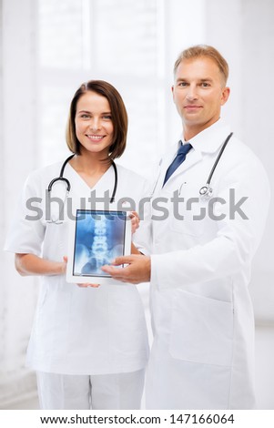 healthcare, medical and radiology - two doctors showing x-ray on tablet pc