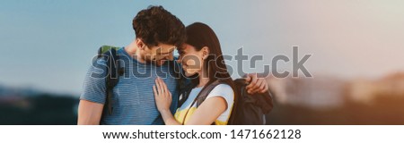 panoramic shot of handsome man and asian woman smiling and hugging outside 