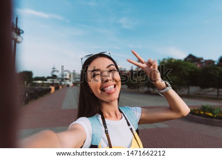 attractive and asian woman taking selfie and sticking out tongue