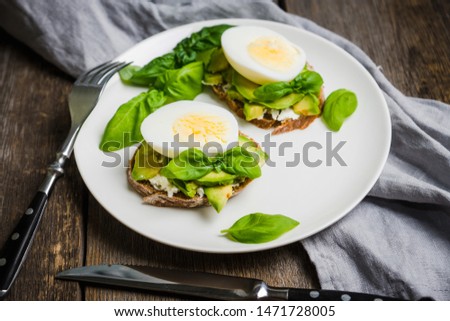Sandwich with avocado, egg, cheese and basil leaves. Selective focus. Shallow depth of field.