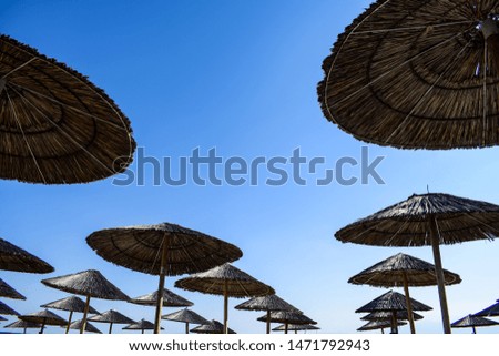 Wooden beach umbrellas under the blue sky. Space for text. 