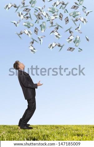 Surprised businessman and flying dollar banknotes against blue sky 