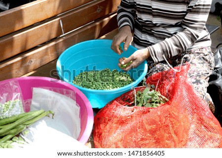 Local woman extracting peas at market