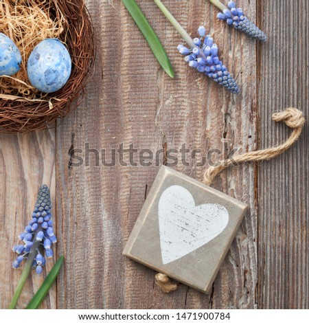 Easter background with eggs, blue hyacinth flowers and  wooden heart, top view on rustic wood, square composition