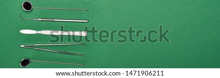 panoramic shot of set with dental tools and scissors isolated on green 