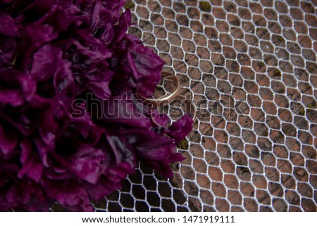 wedding rings lie on a grid of red bricks. Wedding rings lie next to a terry purple poppy flower. preparation for the wedding ceremony.