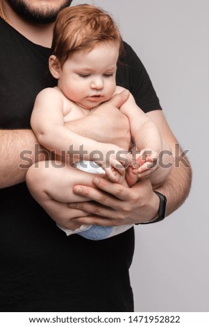 Father keeping little baby in hands and kissing kid
