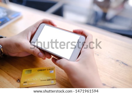 Close up of woman using blank cell phone and credit card sending massages on the coffee shop.