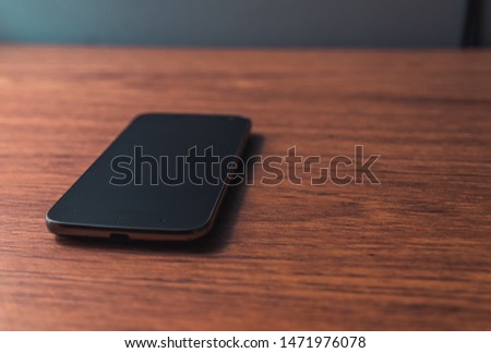Office workplace with text space. Modern black smartphone isolated on wooden table. Smartphone  over wooden board