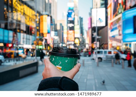 Detail of a hand holding a green coffee glass with New York City in the background - Beautiful city with blurred colors - Close-up