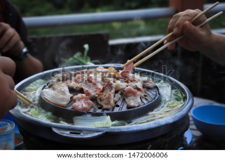 A family enjoy eating buffet of grill pork,  Thai barbecue Grill Pork on hot pan buffet, Moo kra ta (thai word) 

 Royalty-Free Stock Photo #1472006006