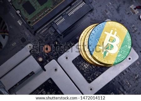 golden shining bitcoins with flag of saint vincent and the grenadines on a computer electronic circuit board. bitcoin mining concept.