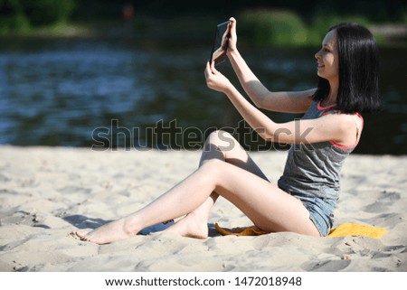 young woman with gadget - digital tablet on the beach on sand near water