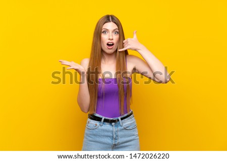 Young woman over isolated yellow background making phone gesture and doubting