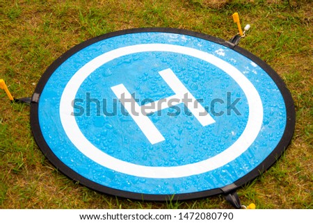 Blue landing place for drone with drops of water. The Landing Parking Pad take off platform for copter is used in high lawn and dusty ground in order to deface the spoilage of a high priced aircraft