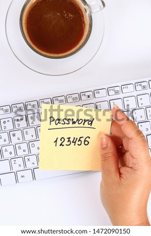 The password on the sticker is a note on the white desktop next to the coffee mug and the keyboard. Top view, flat layout