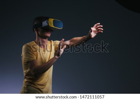 technology, gaming, entertainment and people concept - young man with virtual reality headset or 3d glasses. Studio shot, gray background.