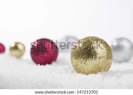 Christmas decoration balls in different colors on a (artificial) snow ground.