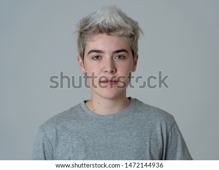Close up portrait of young transgender teenager male with natural and neutral face and beautiful blue eyes. Isolated on neutral background. In People Diversity Human Beauty and Emotions concept. Royalty-Free Stock Photo #1472144936