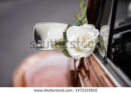 picture of a wedding rose decoration at the quarter glass of an old car