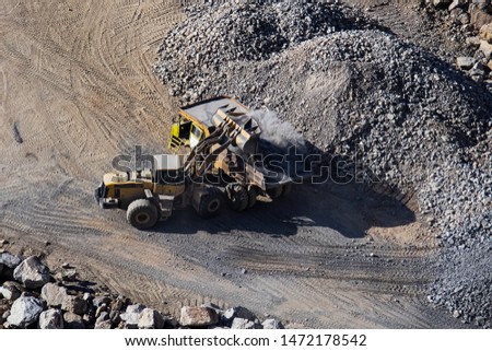 Excavator loading dumper truck on mining site stock photo