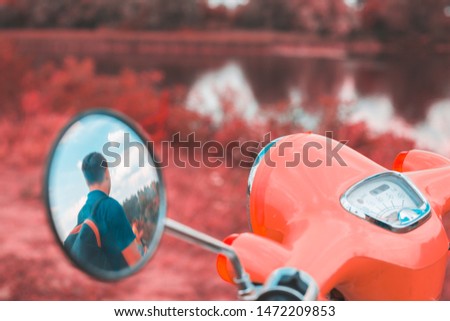 Reflection of a man in the side mirror of a motorbike
