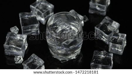 Shot of vodka with ice cubes against black background. Alcohol drink vodka tequila