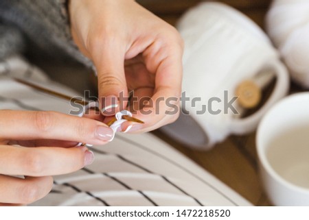 girl in a warm gray sweater knits sitting on a sofa in a cozy interior hygge