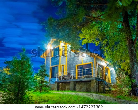 Lighted cottage with panoramic Windows. Two-storey house in the woods. Cottages for rent. Family vacation in nature. Construction of country houses.